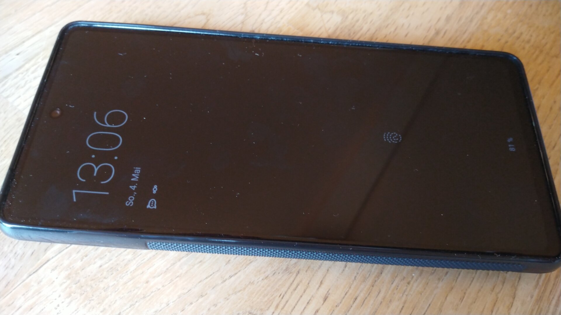 Foto des Pixel 7 mit einer schwarzen Handy-Hülle auf einem Holztisch. Das schwarze Display zeigt die Uhrzeit.